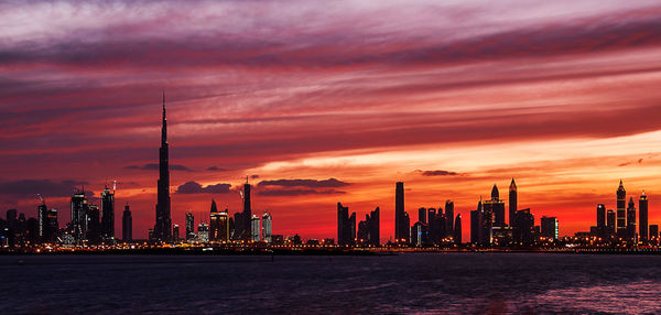 Sea and cityscape against sky at sunset