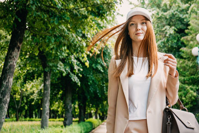 Portrait of smiling young woman standing against trees