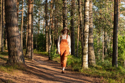 Woman botanist with backpack on ecological hiking trail in forest. naturalist exploring wildlife