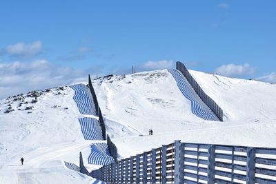 Built structure on snow covered mountain against blue sky