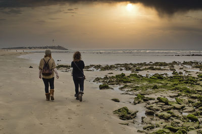 Rear view of women on beach during sunset