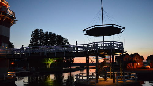 Bridge over river against clear sky at sunset