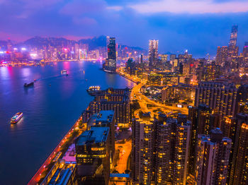 High angle view of illuminated city by sea at night