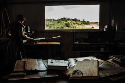 Woman working in a workshop with wooden panels on foreground, low key