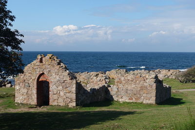 Church ruin by sea against sky