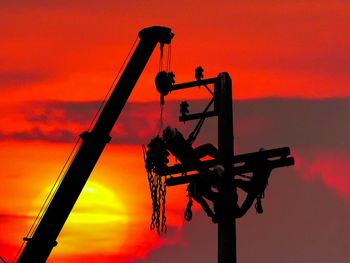 Low angle view of silhouette crane against sky during sunset