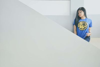 Portrait of a young woman sitting on wall