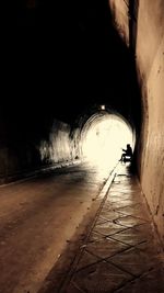 Side view of silhouette person sitting on bench in tunnel