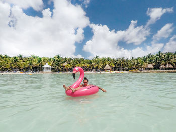 Young woman relaxing on pool raft in sea during vacation