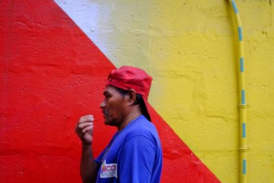 Side view of a man drinking glass against wall