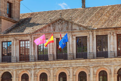 Low angle view of flags hanging on building against sky