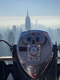 Close-up of coin-operated binoculars against buildings in city