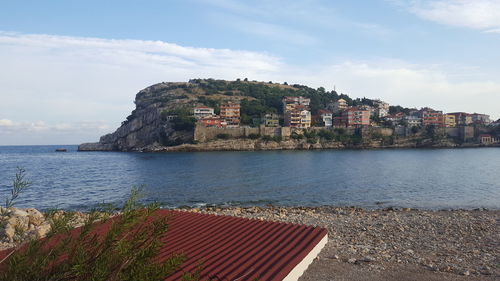 Scenic view of sea by townscape against sky