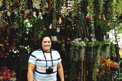 Portrait of smiling woman standing against plants