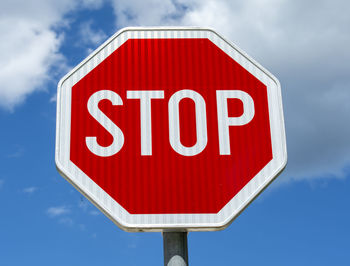 Red octagonal stop sign on a metal pole with cloudy sky in the background. road stop symbol.