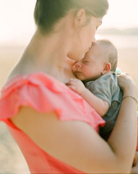 Close-up of mother kissing baby girl on forehead