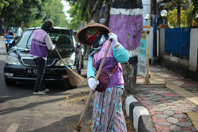 Woman standing by car on street