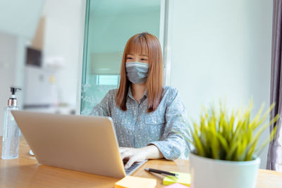 Woman using phone while sitting on table