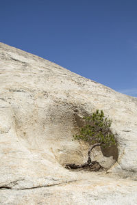 Low angle view of rocks against clear blue sky