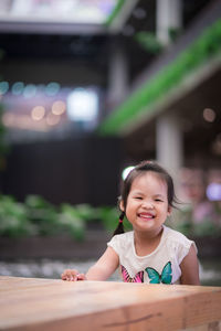 Portrait of smiling girl sitting on table