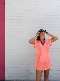 Young woman standing by white wall