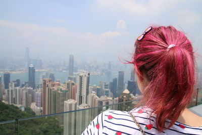 Rear view of woman with dyed hair against cityscape