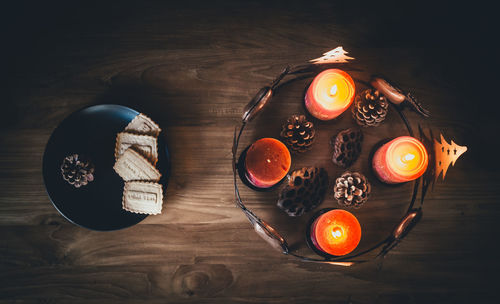 Directly above shot of lit candles by cookies table during christmas