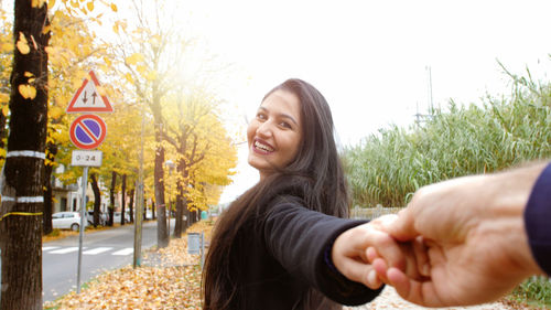 Portrait of young woman standing against trees