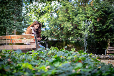 Woman standing by plants against trees