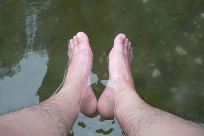 Low section of men feet in water
