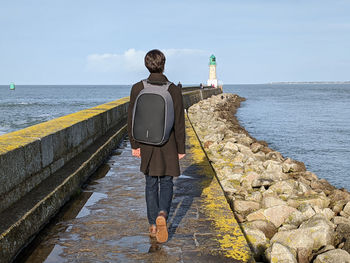 Rear view of man standing on rock by sea