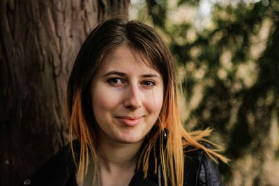 Portrait of teenage girl against tree trunk