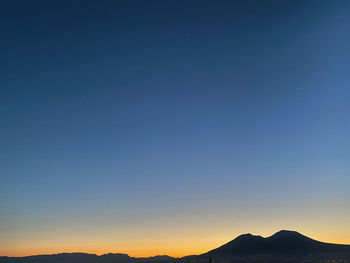Scenic view of silhouette mountains against clear sky during sunset