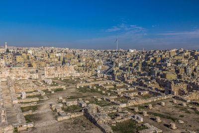 High angle view of city buildings against blue sky