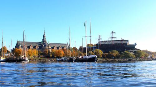 Boats in river against clear blue sky