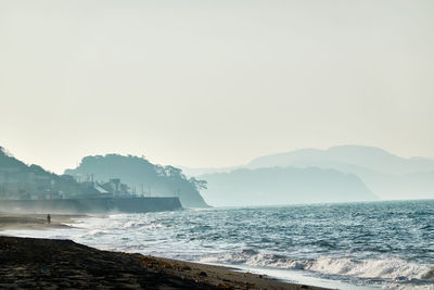 Scenic view of sea against clear sky in foggy morning