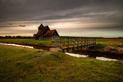 Low angle view of built structure on field against cloudy sky