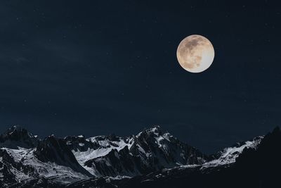 Scenic view of snowcapped mountains against sky at night