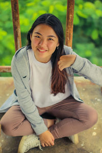 Portrait of a smiling young woman sitting outdoors