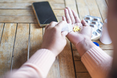 Cropped hands of woman holding pills