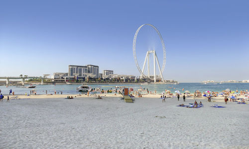 People on beach by sea against clear sky