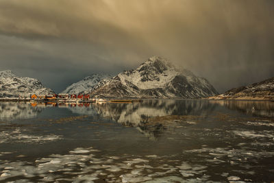 Scenic view of lake by snowcapped mountains against sky