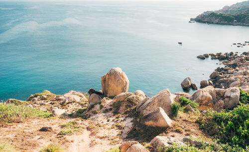 High angle view of rocks by sea against sky