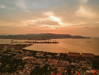 High angle view of sea and cityscape against sky during sunset