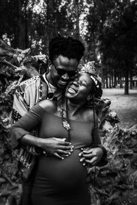 Young couple standing against trees