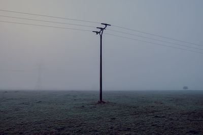 Electricity pylon on field against sky
