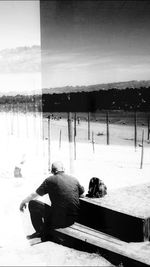 Man sitting on bench by lake