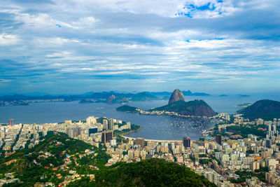 High angle view of city by sea against sky