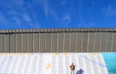 People standing by swimming pool against blue sky