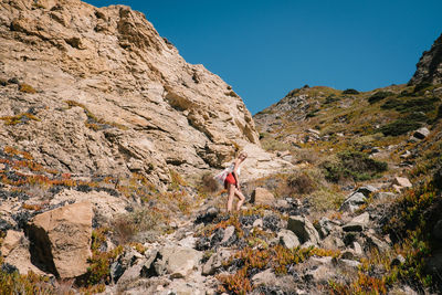 Low angle view of woman hiking on mountain against clear sky